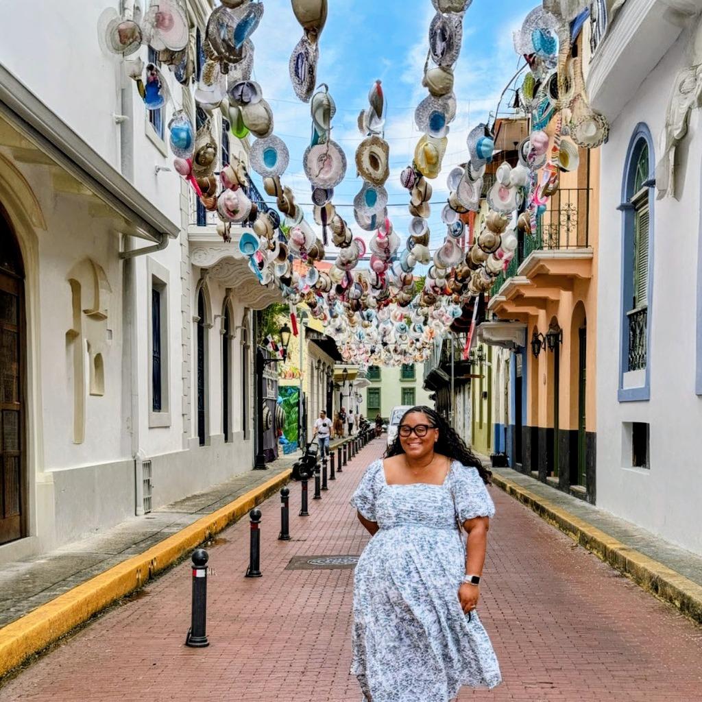 Marien walking through a vibrant street with hanging hats